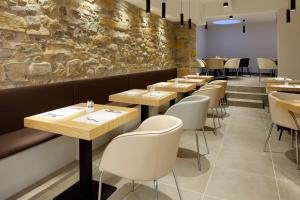 a restaurant with wooden tables and white chairs at HOTEL ARRiZUL CONGRESS in San Sebastián