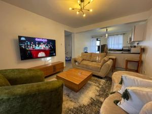 a living room with two couches and a flat screen tv at Cynergy Home in Nairobi