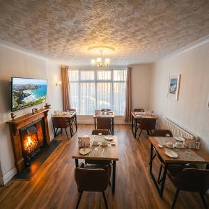 a restaurant with tables and a fireplace in a room at Trevellis Bed and Breakfast in Newquay