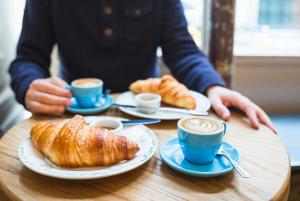 a person sitting at a table with cups of coffee and croissants at Affittacamere Casa Florens Guest House in San Benedetto del Tronto