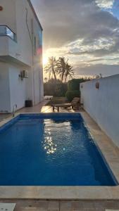 a large blue swimming pool next to a building at villa baya midoun in Midoun +16 photos