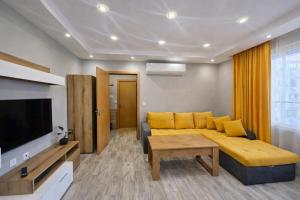a living room with a yellow couch and a television at Boutique apartment yellow 1 in Plovdiv