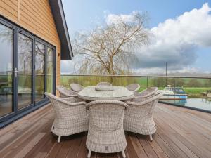 a patio with a table and chairs on a deck at Swing Bridge Cottage in Brandesburton