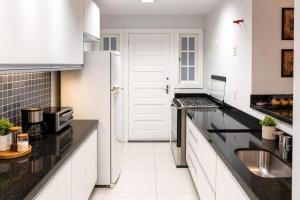 a kitchen with white cabinets and black counter tops at Casa Aconchegante com Vista pertinho do Centro Histórico in Petrópolis