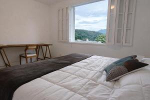 a bedroom with a large bed with a large window at Casa Aconchegante com Vista pertinho do Centro Histórico in Petrópolis
