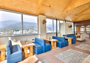 a restaurant with blue chairs and tables and windows at Saltstayz Autograph - Rishikesh Near Triveni Ghat in Rishīkesh +64 photos