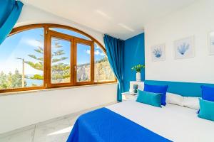 a blue and white bedroom with a large window at Estate4home - Suites Margar in Massa Lubrense