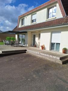 a house with a patio and a table and chairs at Villa l'Escale in Daubeuf-Serville