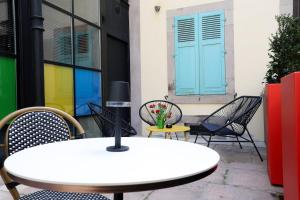 a table and chairs in front of a building with blue doors at Le Quai Verrière in Belfort
