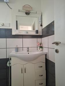 a bathroom with a white sink and a mirror at Corddora Apartman in Mezőkövesd