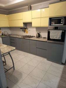a kitchen with yellow cabinets and a stove top oven at SweetHome in Ternopil