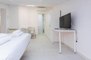 ein weißes Schlafzimmer mit einem Fernseher auf einem Tisch in der Unterkunft Still Loft in Coslada