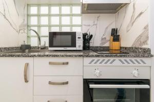 eine weiße Küche mit Spüle und Mikrowelle in der Unterkunft Still Loft in Coslada + 21 Fotos