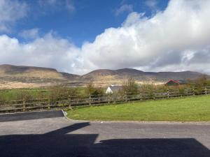 a road with a fence and mountains in the background at Dingle Lispole Garden Suite 10 B in Lispole