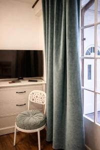 a chair sitting in front of a window with a television at The Old Coach Retreat in Rheinfelden