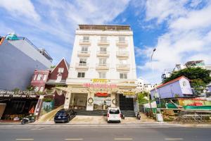 a tall white building with cars parked in front of it at Ngoc Nguyen Anh Hotel Da Lat in Da Lat