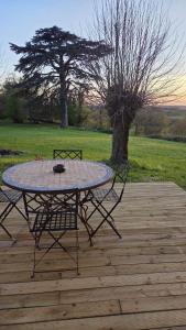 a table and chairs sitting on a wooden deck at Petit Gîte à la campagne in Brains-sur-Gée