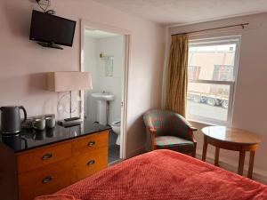 a hotel room with a bed and a chair and a window at Shipwright Inn in Pembroke Dock