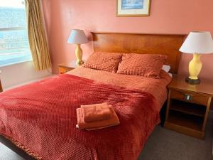 a bedroom with a red bed with a red blanket at Shipwright Inn in Pembroke Dock