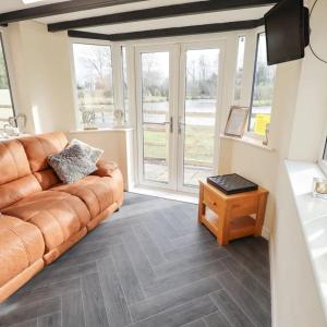 a living room with a leather couch and a table at Butterswood Lakes in Goxhill