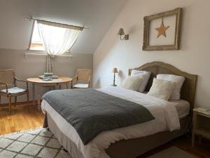 a bedroom with a bed and a table and a window at La Suite du 12 Maison d hôtes in Brie