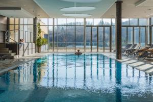 a large swimming pool in a building with windows at Atlantida Boutique Hotel in Rogaška Slatina