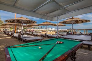 a pool table in front of a beach with umbrellas at Elysees Dream Beach Hotel-By AMARINA Hotels & Resorts in Hurghada