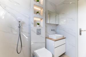 a white bathroom with a shower and a toilet at Azure Edge - Seafront View - Beach Stay in Tigaki