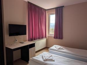 a hotel room with two beds and a desk with a television at Hotel Poli in Blagoevgrad