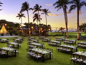 a group of tables and chairs in a field with palm trees at Fairmont Orchid in Waikoloa +233 photos