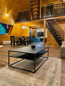 a living room with a table and a staircase at Cabana Bradova Jacuzzi & Heated Pool A-Frame in Bîrsana +19 photos