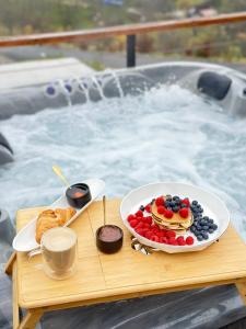 a tray of food on a table in front of a hot tub at Cabana Bradova Jacuzzi & Heated Pool A-Frame in Bîrsana