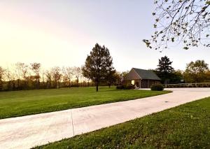 a driveway with a house and a grass field at Set on peaceful 5 acres, 5 min from town, Private Building, Level 2 EV Charger in Bloomington