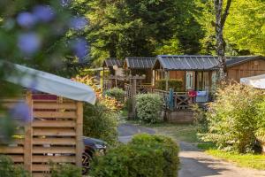 a wooden cabin in the woods with a fence at camping Le moulin in Patornay