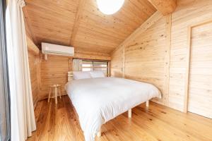 ein Schlafzimmer mit einem Bett in einer Holzhütte in der Unterkunft Amakusa LogHouse UmiOTO 海音 in Amakusa