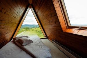 a bed in a room with a large window at Cabana Bradova Jacuzzi & Heated Pool A-Frame in Bîrsana