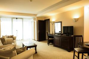 a living room with a couch and a desk with a television at Apartament executive vedere munte Alpin Resort Poiana Brasov in Poiana Brasov