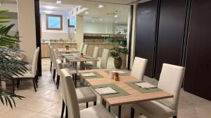 a dining room with wooden tables and white chairs at Kairos Garda Hotel in Castelnuovo del Garda +86 photos