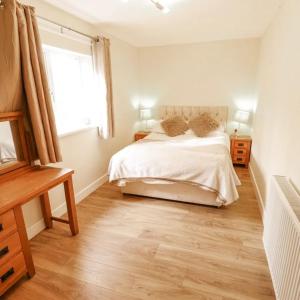 a bedroom with a bed with white sheets and a window at Butterswood Lakes in Goxhill