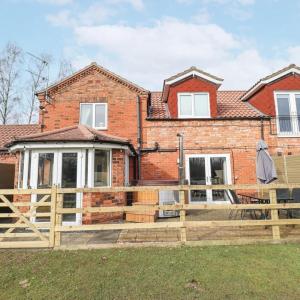 a brick house with a wooden fence in front of it at Butterswood Lakes in Goxhill