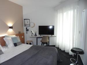 a bedroom with a bed and a desk with a television at Logis Hotel Restaurant Le Jardin Délice in Saint-Victor