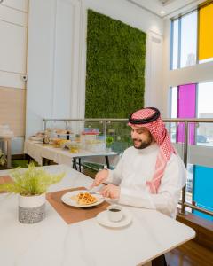 a man sitting at a table with a plate of food at Dara Qurtubah Hotel in Riyadh