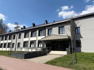 a large white building with a tree in front of it at Apartament Daisy Pszczyna Centrum in Pszczyna