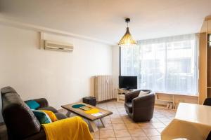 a living room with a couch and chairs and a tv at Grand appartement spacieux au centre de Chambéry, gare à pied in Chambéry