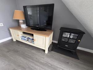 a television sitting on a stand with a stove at 124, Three bed two storey chalet on Bermuda holiday park, Hemsby - Sleeps 7, bed linen and towels included with onsite entertainment and further entertainment close by - includes balcony in Great Yarmouth