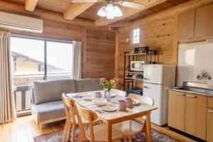 eine Küche und ein Wohnzimmer mit einem Tisch und einem Sofa in der Unterkunft Amakusa LogHouse UmiOTO 海音 in Amakusa
