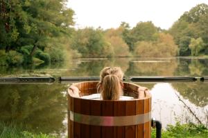 a woman is sitting in a wooden barrel by a lake at Crafted at Powdermills in Battle