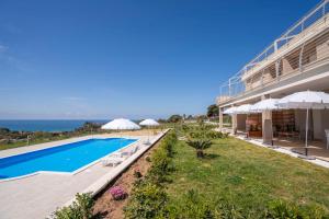 a resort with a swimming pool with umbrellas and the ocean at Villa Adele con piscina privata vicino Tropea - per 16 persone in Torre Marino