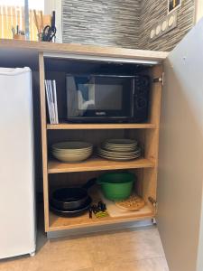 a kitchen cabinet with a microwave and plates in it at Super studio aux portes de Bordeaux ! in Gauriaguet +9 photos