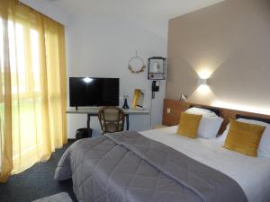 a bedroom with a large bed and a television at Logis Hotel Restaurant Le Jardin Délice in Saint-Victor